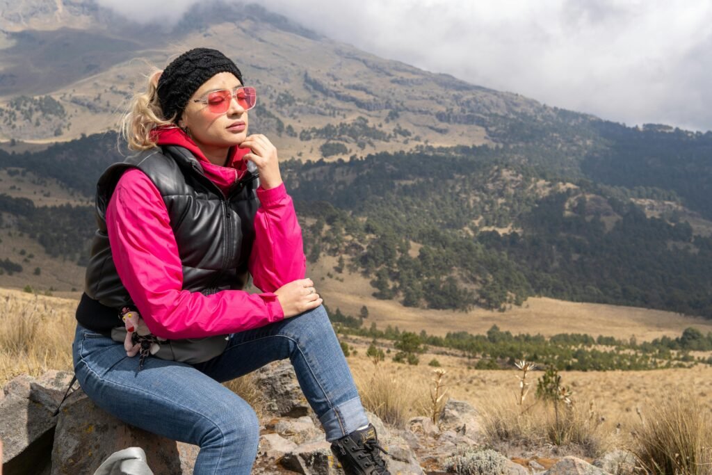 Woman in pink jacket enjoys breathtaking mountain views hiking in Puebla, Mexico.